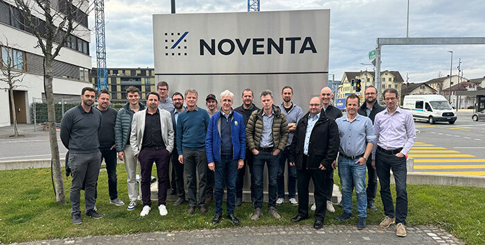 Erfahrungsgruppe Lean bei Noventa. Personen stehen vor dem Firmenschild im Außenbereich von Noventa.