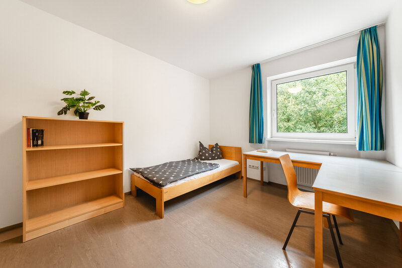 Ein hell eingerichtetes Einzelzimmer mit einem Holzbett, einem Schreibtisch und einem Bücherregal. | © FH Kufstein Tirol