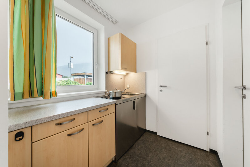Eine gut beleuchtete Küche mit modernen Annehmlichkeiten. Über der Spüle befindet sich ein Fenster, das Tageslicht hereinlässt und einen Blick nach draußen bietet. | © FH Kufstein Tirol