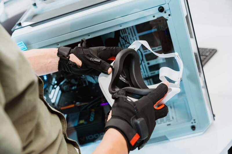 Person mit Datenhandschuhen hält VR-Brille im Web Lab der FH Kufstein Tirol.
