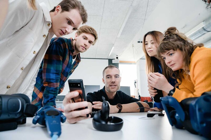 Gruppe von Studierenden und Dozent diskutiert über Smartphone-Interface im Web Lab der FH Kufstein Tirol.