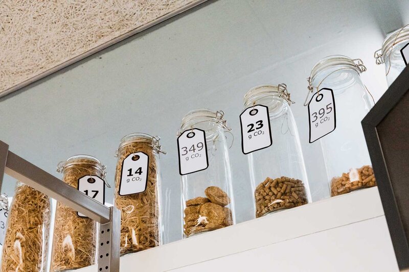 Glasgefäße mit Biomaterialien und CO₂-Angaben zur Emissionsanalyse im Sustain & Estate Lab der FH Kufstein Tirol.