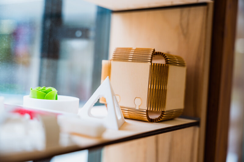 Regalausstellung im Makers Lab der FH Kufstein Tirol mit verschiedenen 3D-gedruckten und gelaserten Objekten aus Kunststoff und Holz.