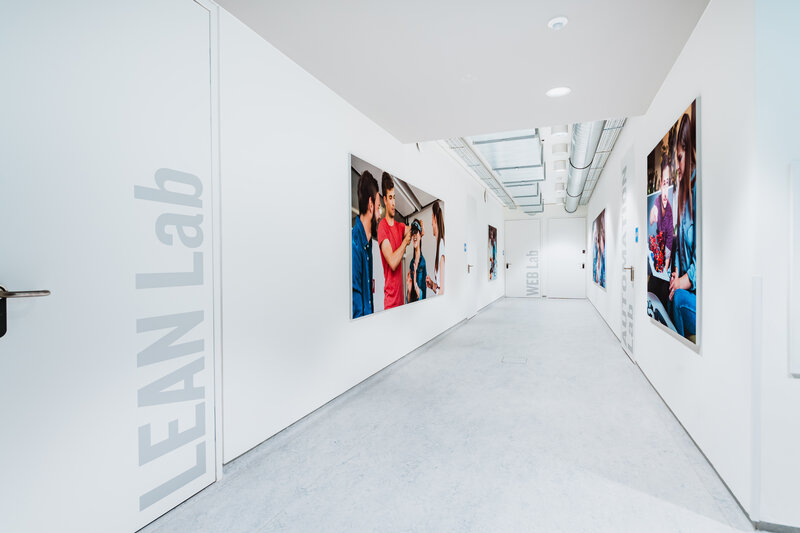 Heller Flur im Laborbereich der FH Kufstein Tirol mit Wandgrafiken und Beschriftungen der Labore, darunter das Lean Lab.