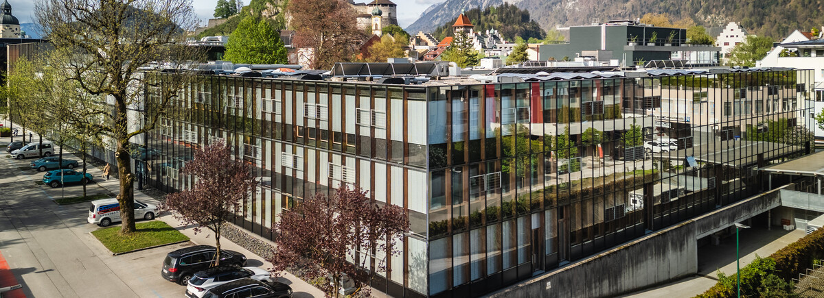 Luftaufnahme des modernen Hauptgebäudes der FH Kufstein Tirol mit Festung und Bergen im Hintergrund