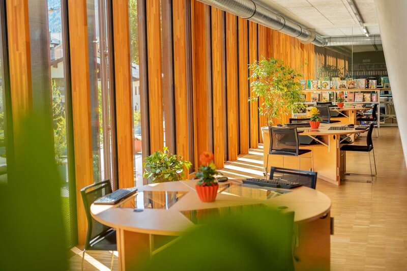 Arbeitsbereich der kubi am Campus der FH Kufstein Tirol mit Holzboden, großen Fenstern, Schreibtischen, Stühlen 