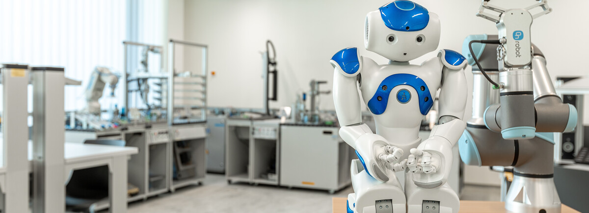 Humanoider Roboter und kollaborativer Roboterarm stehen im Automation Lab der FH Kufstein Tirol.