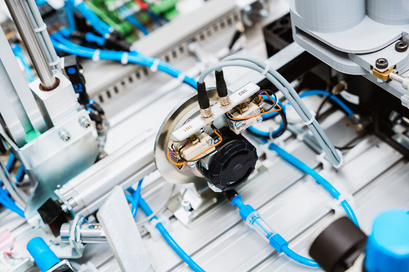 Präzise verdrahtete Steuerungseinheit mit grüner Platine und Kabelverbindungen in einer Laboranlage.