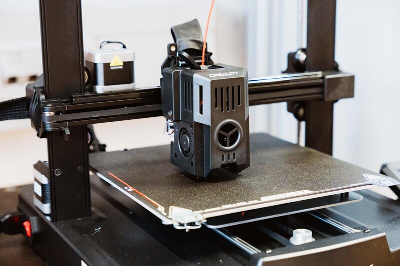 3D-Drucker im Makers Lab der FH Kufstein Tirol beim Aufbau eines Objekts, Nahaufnahme des Druckkopfs mit Filamentzufuhr.