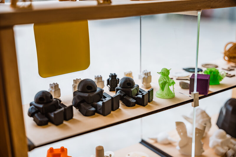 Vitrine im Makers Lab der FH Kufstein Tirol mit farbigen 3D-Druckmodellen, Figuren und technischen Miniaturen.
