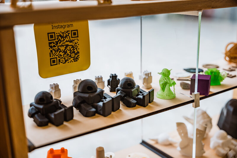 Vitrine im Makers Lab der FH Kufstein Tirol mit farbigen 3D-Druckmodellen, Figuren und technischen Miniaturen.