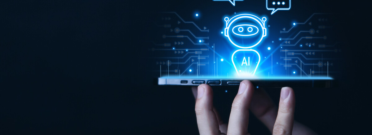 Hand hält ein Smartphone, über dem eine digitale Darstellung eines Chatbots mit der Aufschrift „AI“ schwebt – Visualisierung von künstlicher Intelligenz und digitaler Kommunikation.
