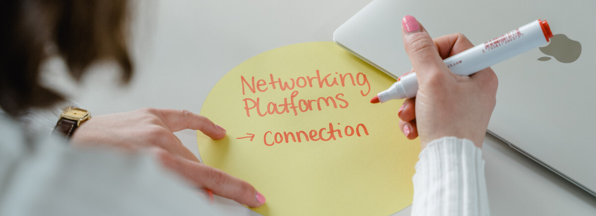 Hand schreibt den Begriff „Networking Platforms – Connection“ auf eine runde Karte – Symbol für Austausch, Kooperation und digitale Netzwerke.