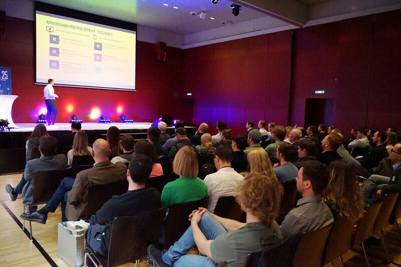 Georg Eder spricht beim 23. PQM-Dialog an der FH Kufstein Tirol vor einem sitzenden Publikum auf einer Bühne.