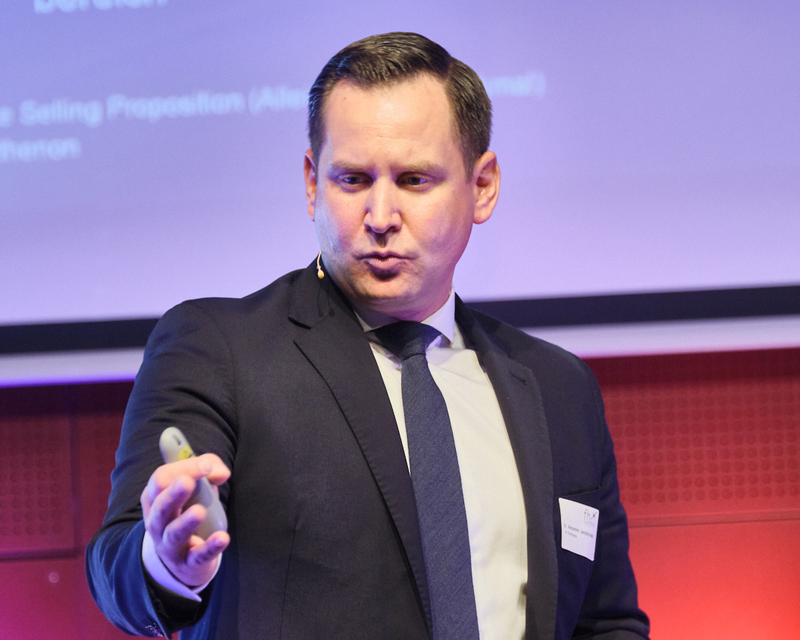 Alexander Jaroschinsky als Speaker auf der hell beleuchteten Bühne beim 14. Internationalen Symposium Restrukturierung