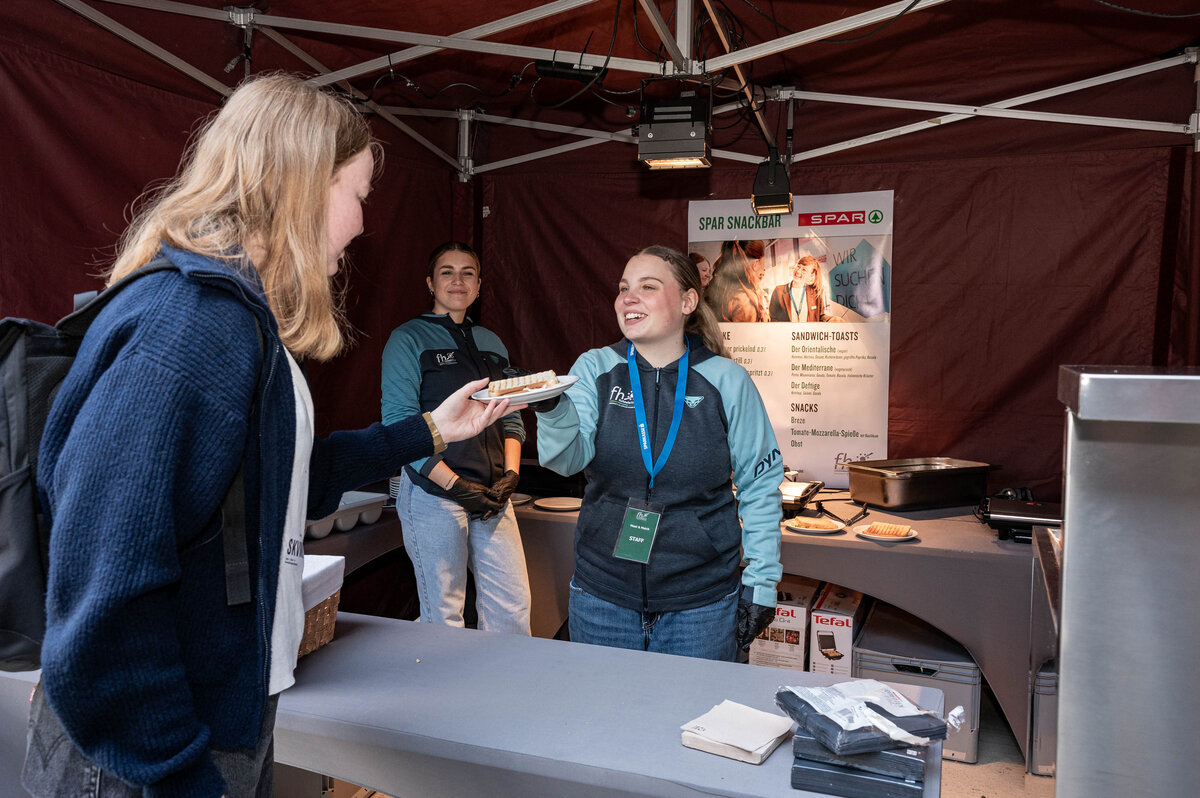 esucher:innen stehen beim Essensstand und tauschen sich auf der Karrieremesse Meet & Match aus.