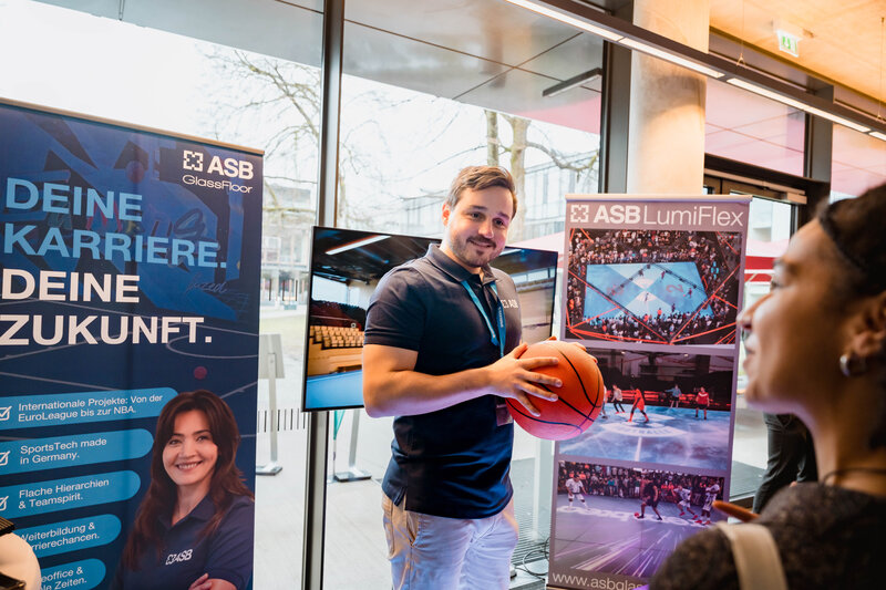 Fabian Bär am Stand von ASB GlassFloor im Gespräch mit Besucher:innen der Meet & Match.  | © FH Kufstein Tirol