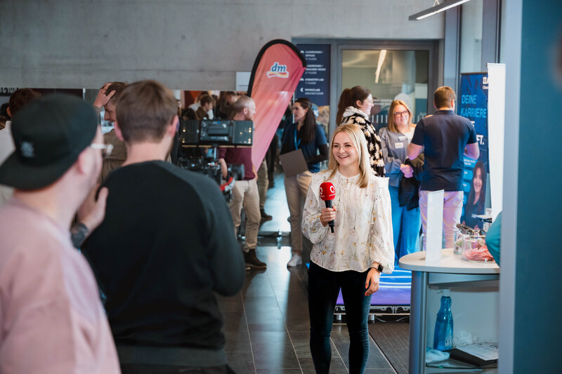 Frau mit Mikrofon spricht auf der Karrieremesse Meet & Match in eine Fernsehkamera | © FH Kufstein Tirol