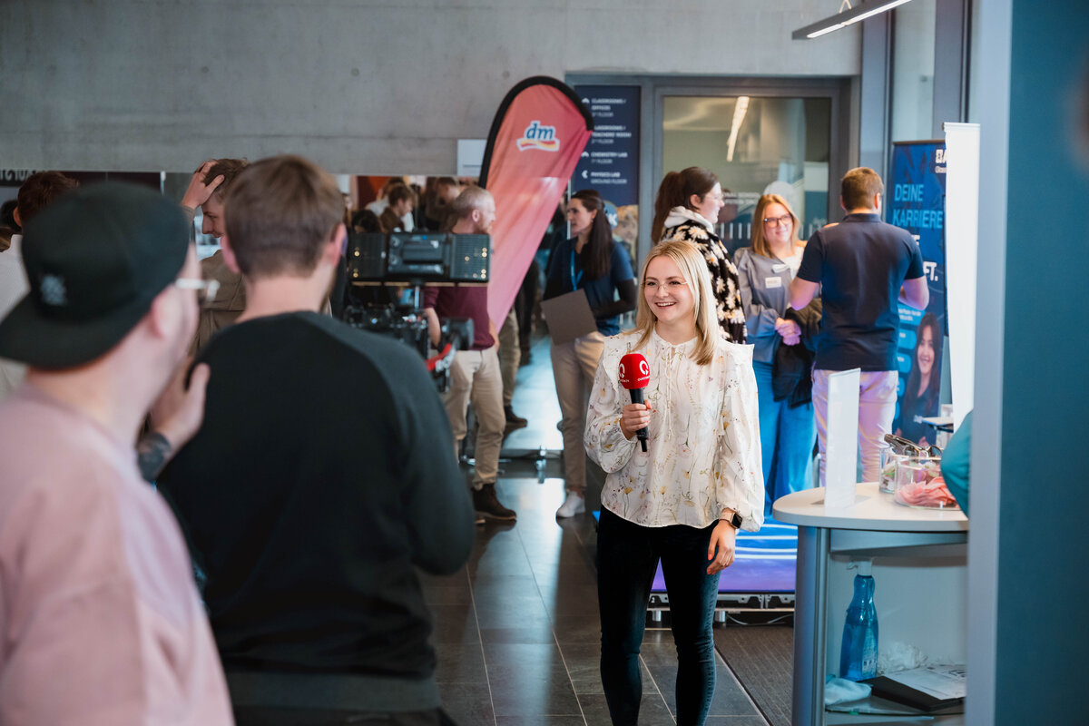 Frau mit Mikrofon spricht auf der Karrieremesse Meet & Match in eine Fernsehkamera | © FH Kufstein Tirol