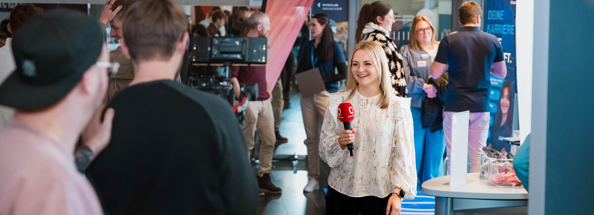 Meet & Match-qtv | © FH Kufstein Tirol Frau mit Mikrofon spricht auf der Karrieremesse Meet & Match in eine Fernsehkamera | © FH Kufstein Tirol