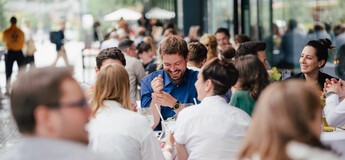 Eine große Gruppe von Personen unterhält sich und lacht beim Homecoming-Event im Außenbereich. | © FH Kufstein Tirol