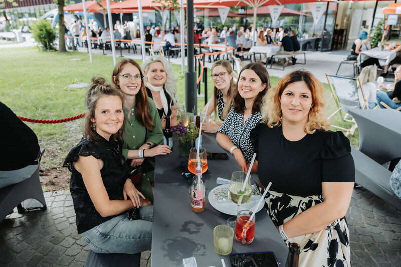 event-homecoming-besucherinnen-tischbereich-haupteingang-2025 | © FH Kufstein Tirol Lachende Gäste am gedeckten Tisch beim Homecoming 2025. | © FH Kufstein Tirol