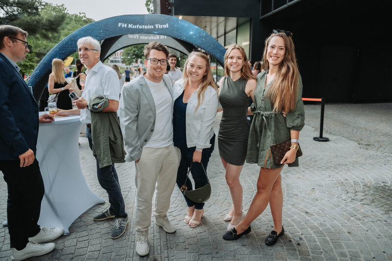 event-homecoming-gruppe-eingangsbereich-zelt-2025 | © FH Kufstein Tirol Teilnehmer:innen stellen sich für ein schnelles Foto vor der Homecoming-Kulisse auf. | © FH Kufstein Tirol