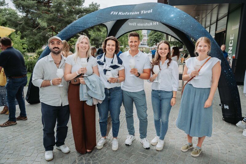 event-homecoming-gruppe-fh-zelt-2025 | © FH Kufstein Tirol Mehrere Teilnehmer:innen halten kurz inne, um für ein Portrait zu lächeln. | © FH Kufstein Tirol