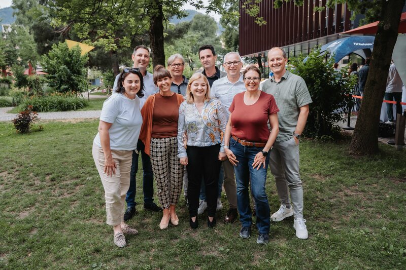 event-homecoming-gruppenfoto-rasen-2025 | © FH Kufstein Tirol Mehrere Gäste stellen sich lächelnd in Zweierreihen für das Foto auf. | © FH Kufstein Tirol
