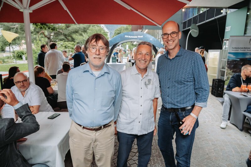 event-homecoming-hoffmann-dietrich-eingangsbereich-2025 | © FH Kufstein Tirol Gäste lächeln in die Kamera vor festlicher Kulisse. | © FH Kufstein Tirol