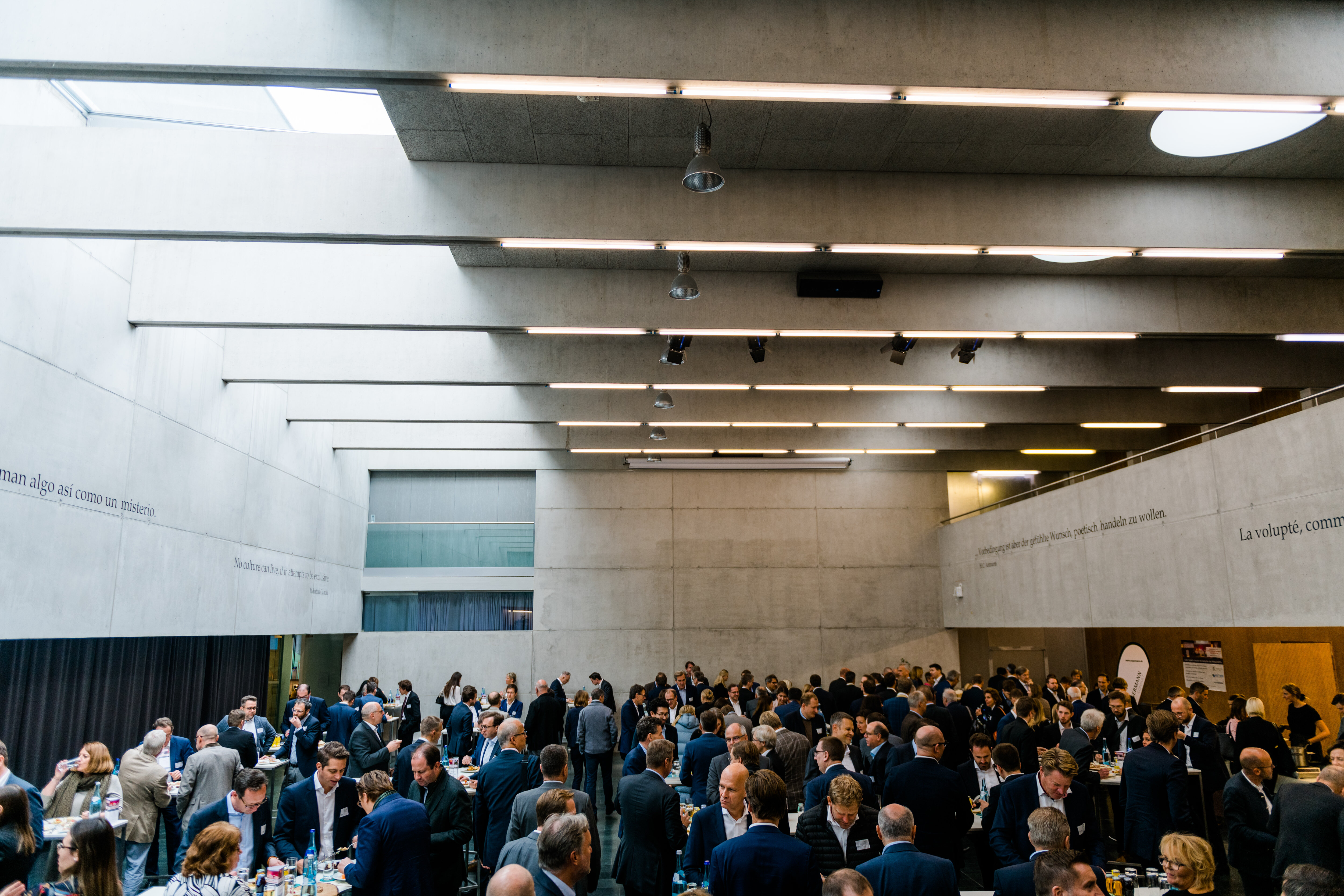 Symp_Aula | © FH Kufstein Tirol Eine große Gruppe von Menschen versammelt sich im modernen Innenbereich der FH Kufstein. | © FH Kufstein Tirol