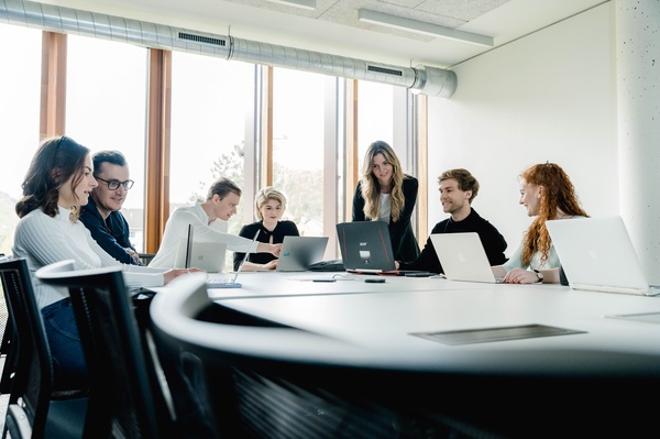 Studierende an der FH Kufstein Tirol sitzen an einem Tisch mit Laptops und diskutieren in einem hellen Raum mit Blick auf die Festung Kufstein. | © FH Kufstein Tirol