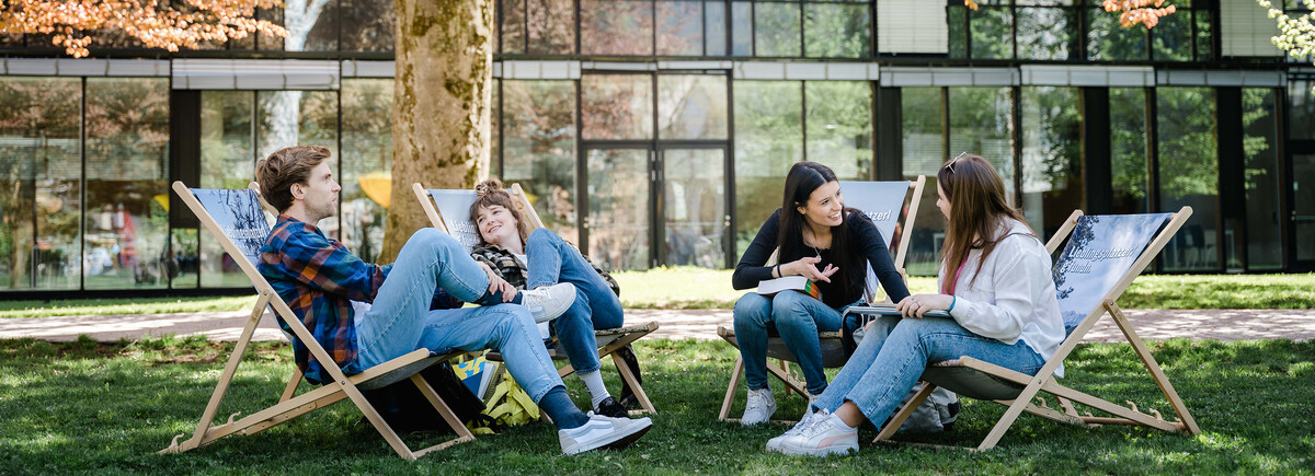 Studienformen | © FH Kufstein Tirol Vier Personen sitzen entspannt im Park und reden freudig miteinander. | © FH Kufstein Tirol