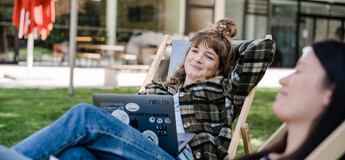 Zwei Studierende der FH Kufstein Tirol arbeiten entspannt im Freien auf Liegestühlen am Campus.