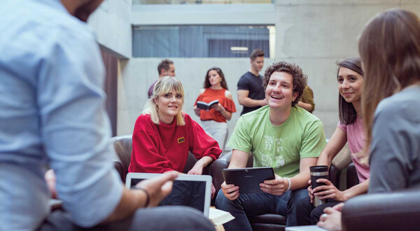 Gruppe von Studierenden der FH Kufstein Tirol arbeitet gemeinsam an einem Projekt in der Aula der Hochschule.