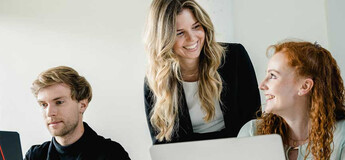Dozentin im Gespräch mit Studierenden bei gemeinsamer Arbeit am Laptop an der FH Kufstein Tirol.