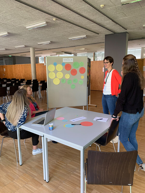 Teilnehmerinnen stehen um den Tisch und vor einem Flipchart | © FH Kufstein Tirol