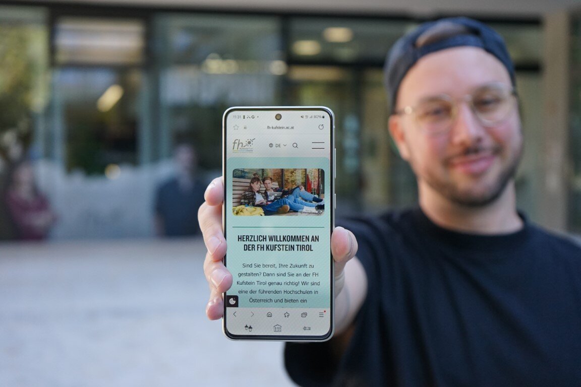 Student-Handy-mobile-Version-FH-Kufstein-Tirol | © FH Kufstein Tirol Student zeigt die mobile Version der neuen Website der FH Kufstein Tirol auf seinem Handy-Display. | © FH Kufstein Tirol