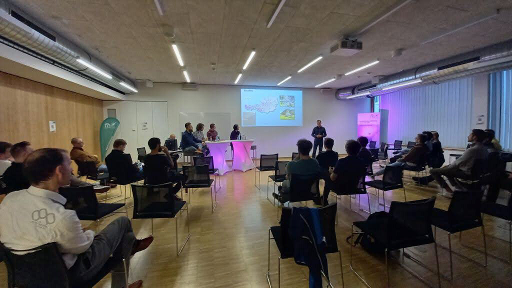 Personen siitzen auf Stühlen und schauen auf eine Projektion an der Wand. | © FH Kufstein Tirol