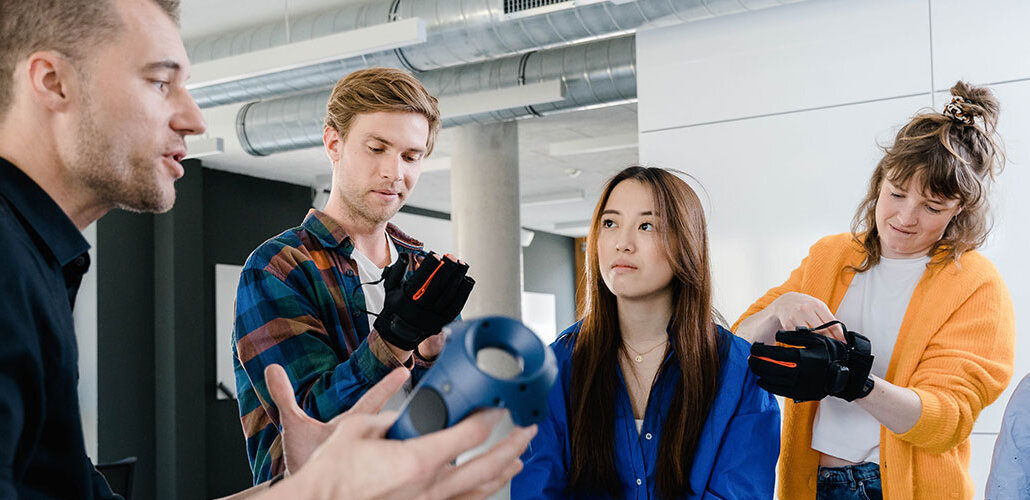 Studierende testen Technik mit VR-Handschuhen.