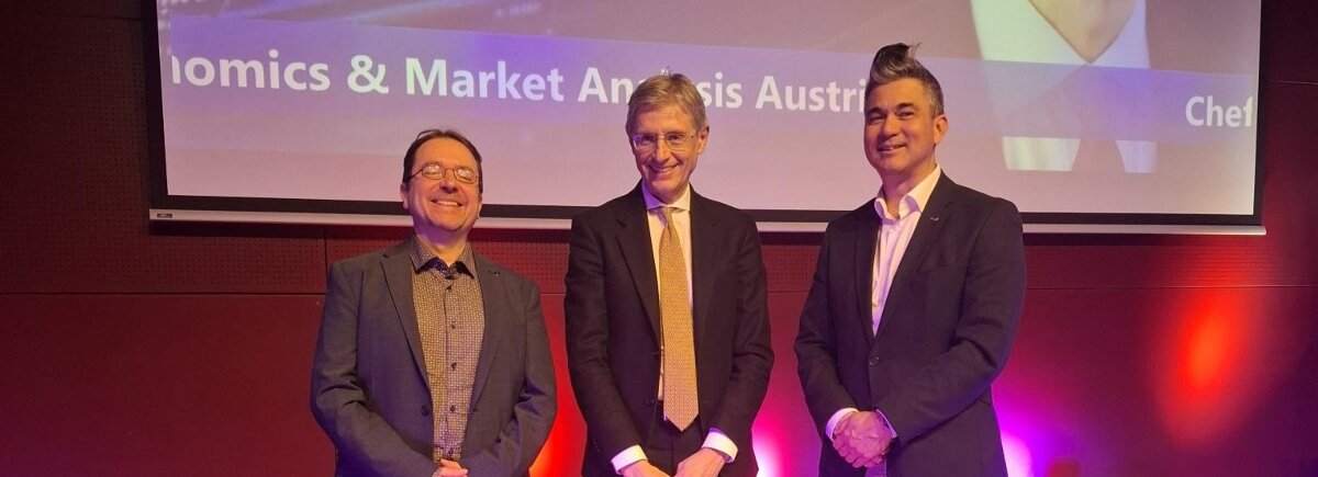 Gruppenfoto auf einer Bühne: Studiengangsleiter Prof. (FH) PD Dr. Christoph Hauser, Mag. Stefan Bruckbauer und der Präsident des Lions Club Kufstein, Volker Steindl, stehen nebeneinander. Der Hintergrund ist in warmen Farbtönen beleuchtet. | © FH Kufstein Tirol 