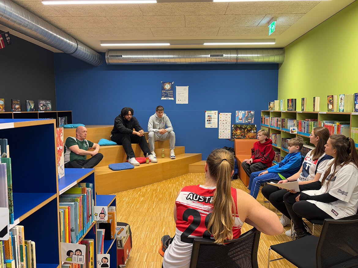 Kinder sitzen um zwei Personen im Leseraum der kubi | © FH Kufstein Tirol