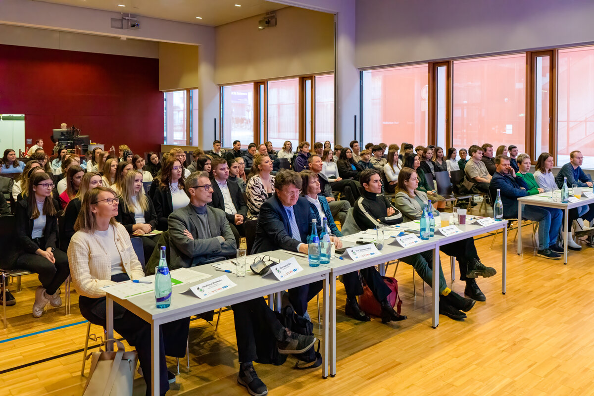 7-Euro-Cash-at-School-Wettbewerb-Publikum-Festsaal-FH-Kufstein-Tirol | © FH Kufstein Tirol Ein Blick ins Publikum des Festsaals der FH Kufstein Tirol: In der ersten Reihe sitzen die Juror:innen des 7€ Cash@School-Wettbewerbs, dahinter die Schüler:innen. | © FH Kufstein Tirol