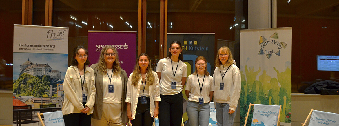projektteam-table-tennis-tournament-fh-kufstein-tirol | © FH Kufstein Tirol Eine Gruppe von sechs jungen Frauen steht in einer Sporthalle vor Bannern der FH Kufstein Tirol, der Sparkasse Kufstein und des Green Event Tirol. Sie tragen Namensschilder und lächeln in die Kamera. | © FH Kufstein Tirol