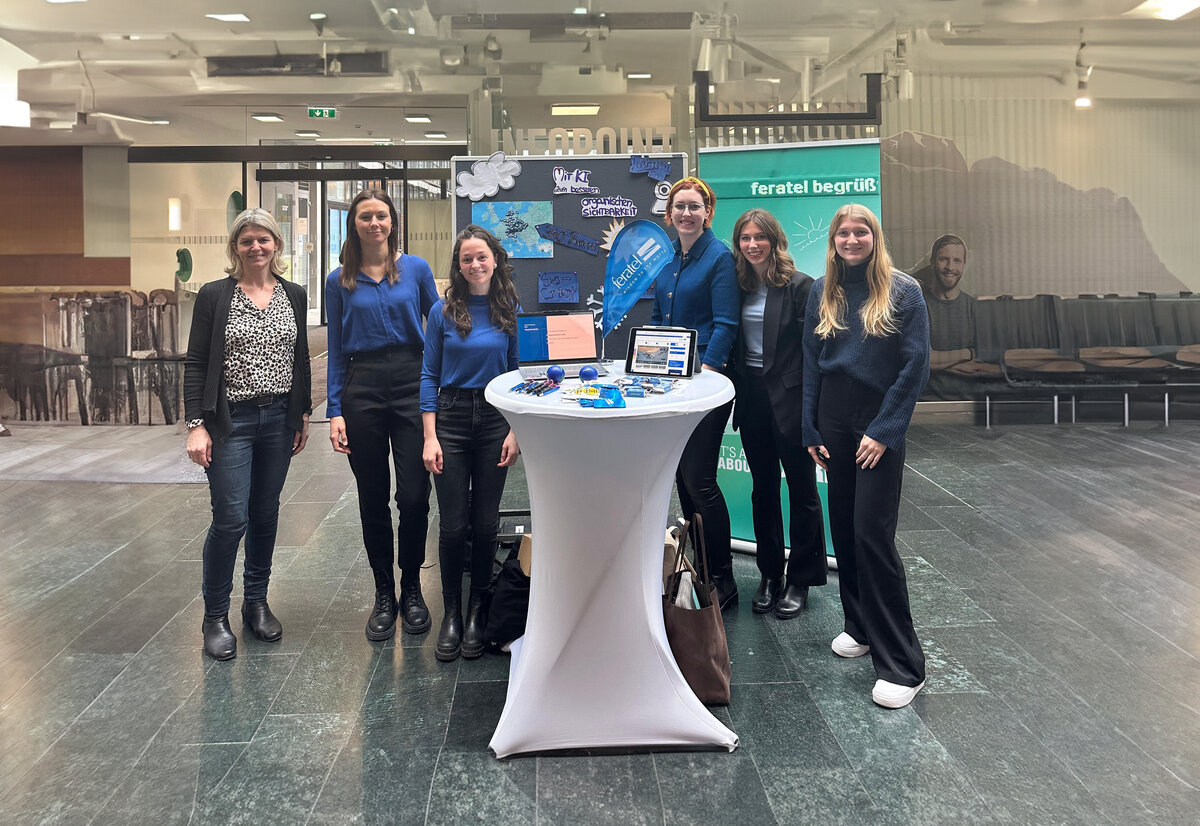 Feratel-Expo1 | © FH Kufstein Tirol ki-adaptiert Mitglieder Praxisprojekt und Ines Zitturi am Expo-Stand in der Aula | © FH Kufstein Tirol ki-adaptiert