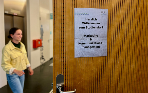 Schild mit Hinweis zum Aufnahmegespräch, Bewerberin tritt vor die Tür | © FH Kufstein Tirol