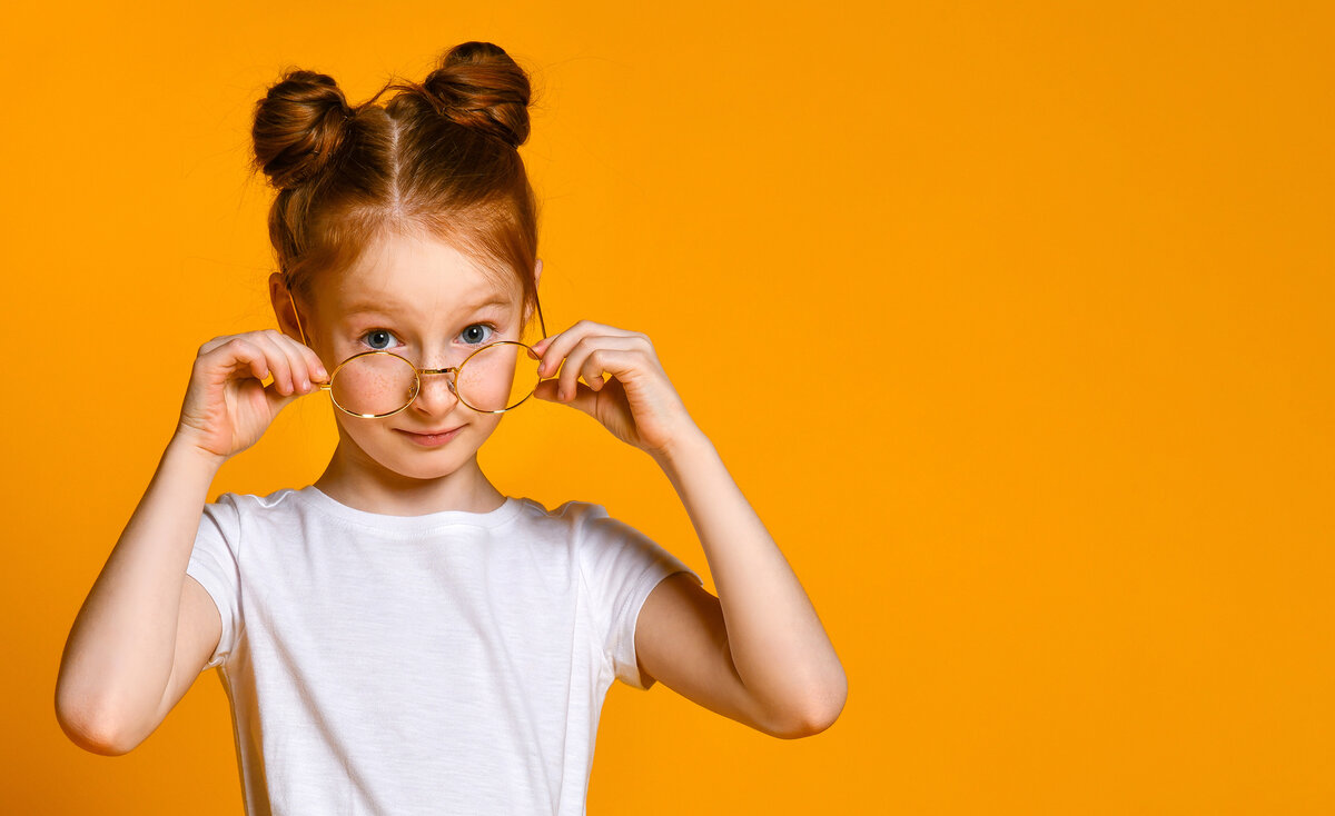 SOS Kinderdorf | © AdobeStock.FAB.1 Kind mit Brille vor orangenem Hintergrund | © AdobeStock.FAB.1