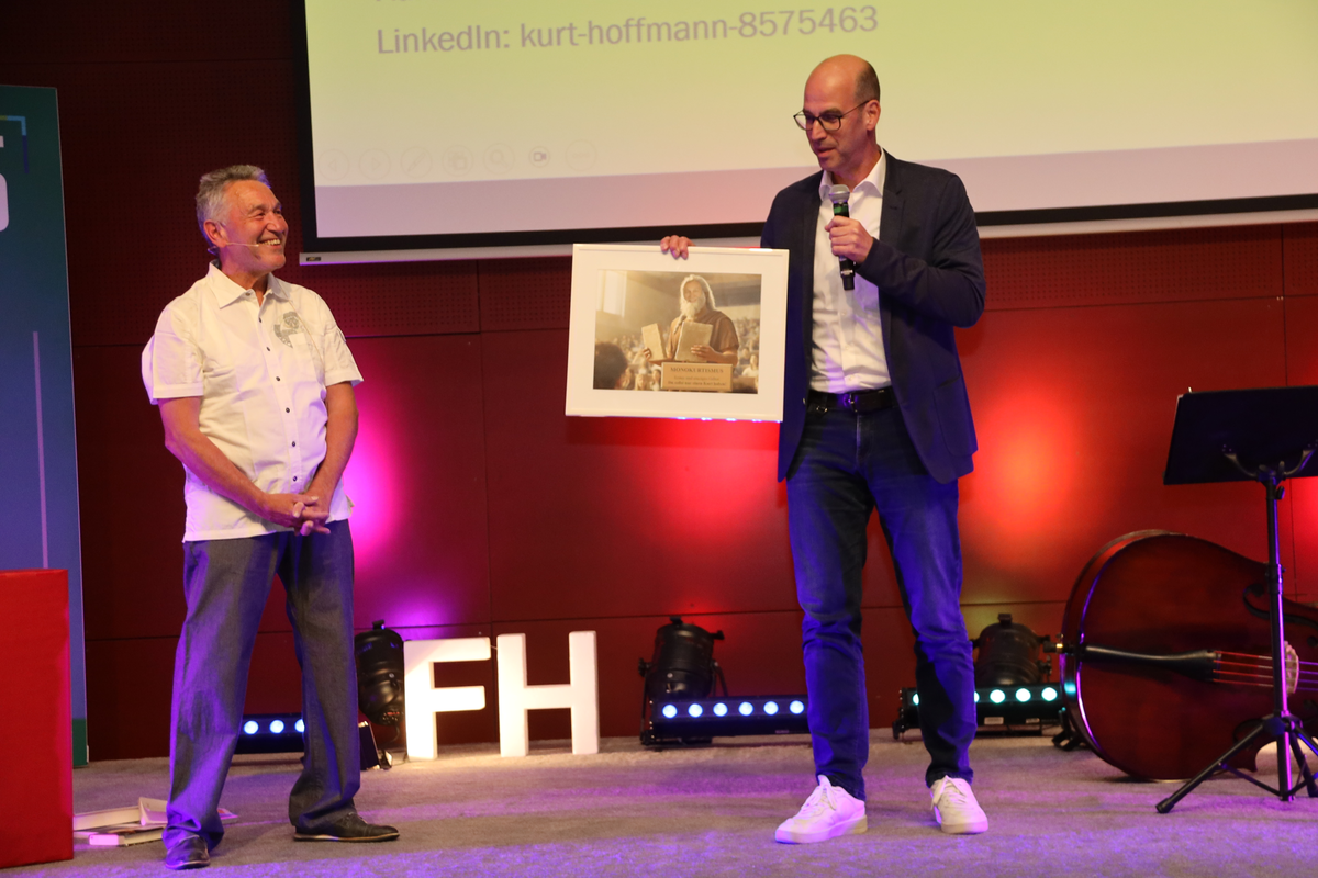 Kurt-Hoffmann-Abschiedsvorlesung-Bild-Monokurtismus | © FH Kufstein Tirol Prof. (FH) Mag. Kurt Hoffmann erhält von Prof. (FH) Dr. Peter Dietrich ein Bild überreicht. | © FH Kufstein Tirol