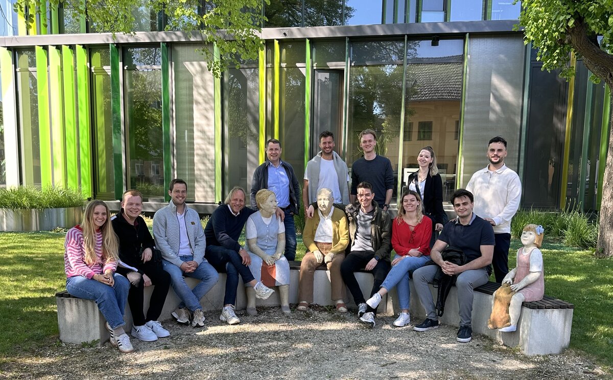 studienreise-ctm-2025 | © FH Kufstein Tirol Eine Gruppe von Personen sitzt draußen in einem Halbkreis auf einer Betonmauer. | © FH Kufstein Tirol