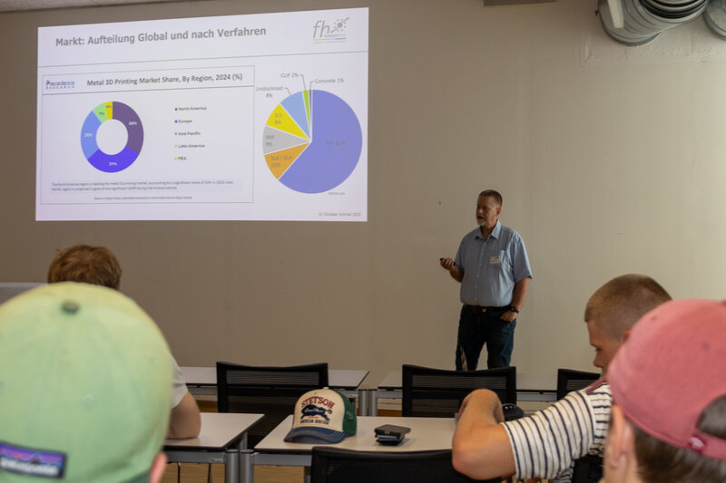 Ein Mann steht in einem Klassenraum und zeigt eine Präsentation. | © FH Kufstein Tirol 